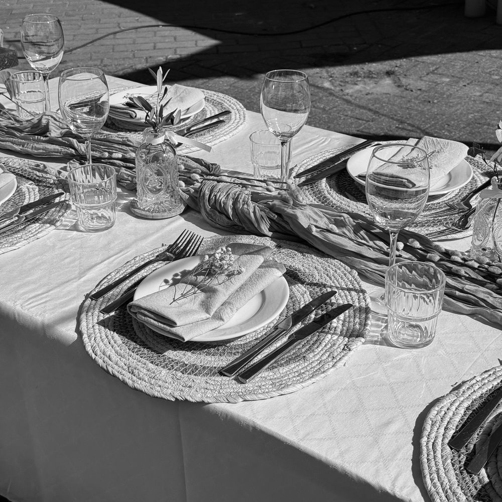 Couvert met rieten placemat, olijftakjes en glaswerk in zwart wit