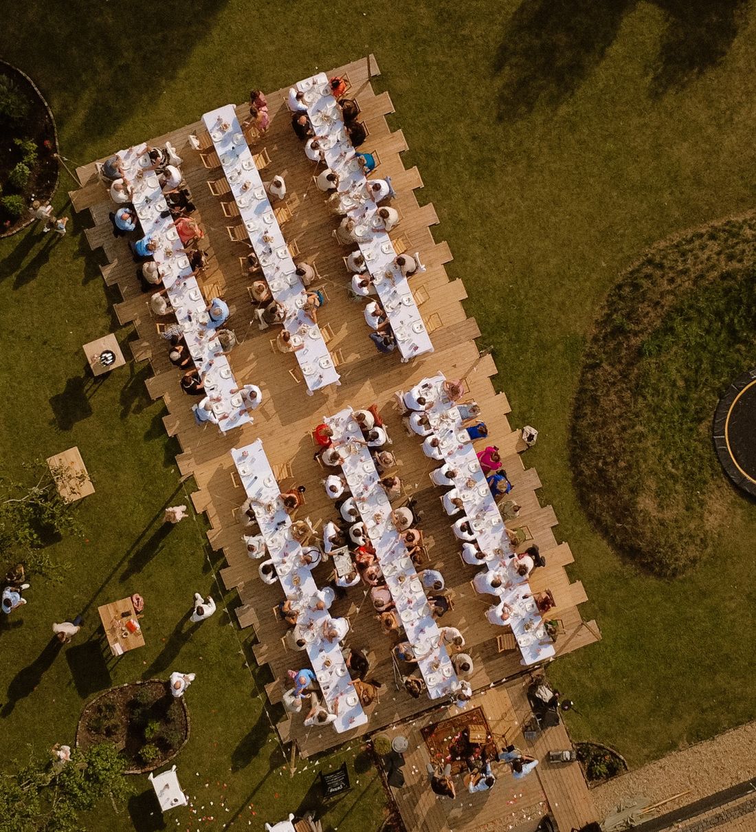 Luchtfoto van een bruiloftsdiner met lange tafels vol gasten